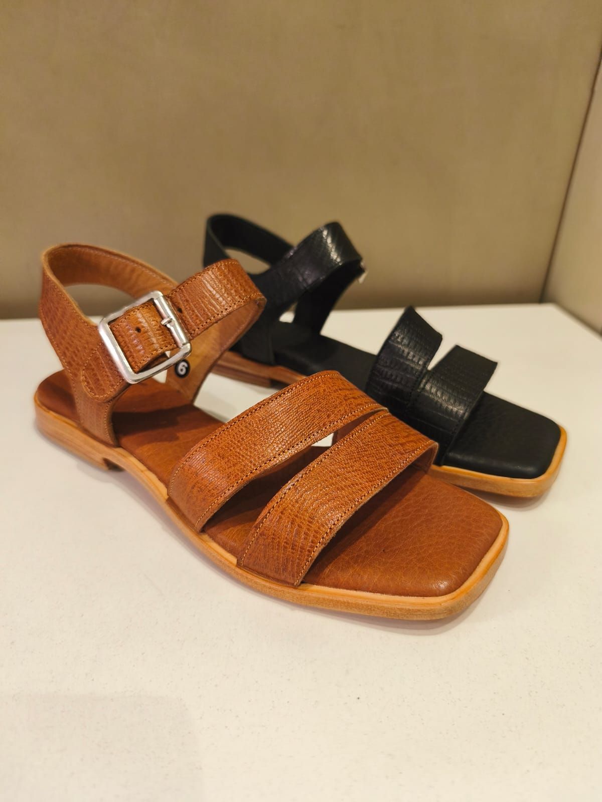 Sandalias de piel marrón y negra con puntera cuadrada y tiras en el tobillo.