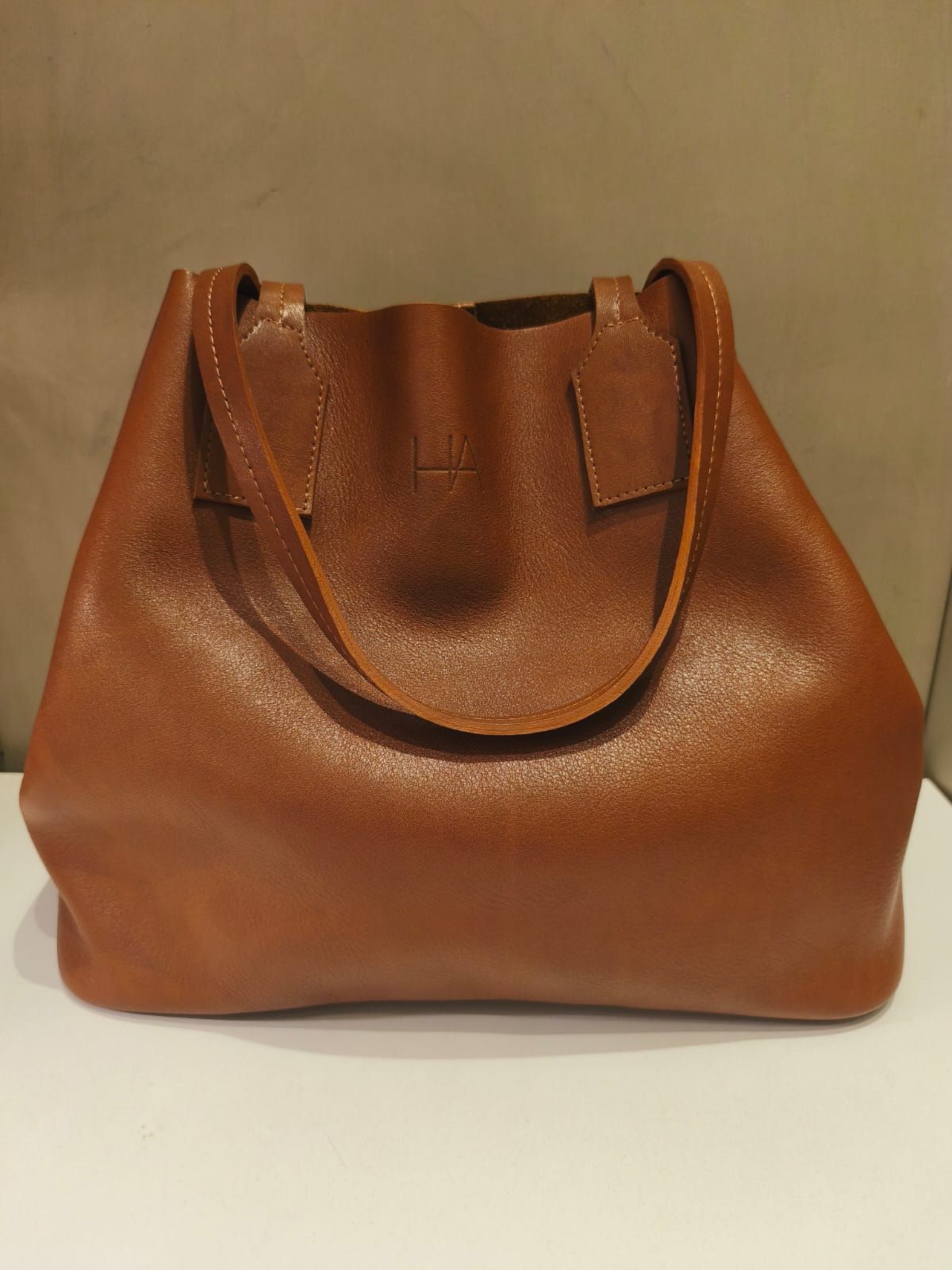 Bolso tote de piel marrón con cierre de cordón y dos asas.