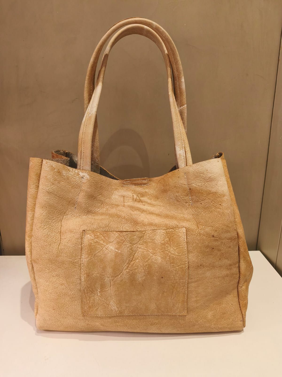 Bolso tote beige con dos asas y bolsillo frontal.