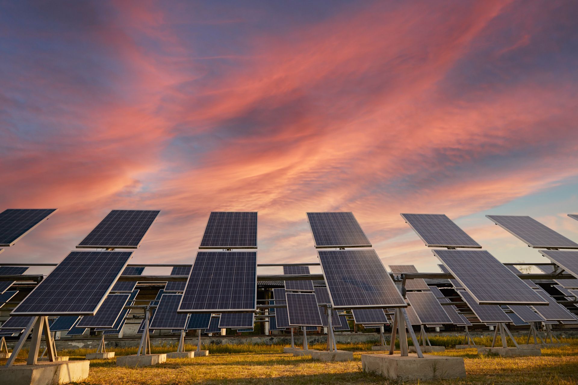 Solar panels angled toward the sky, set against a colorful sunset.