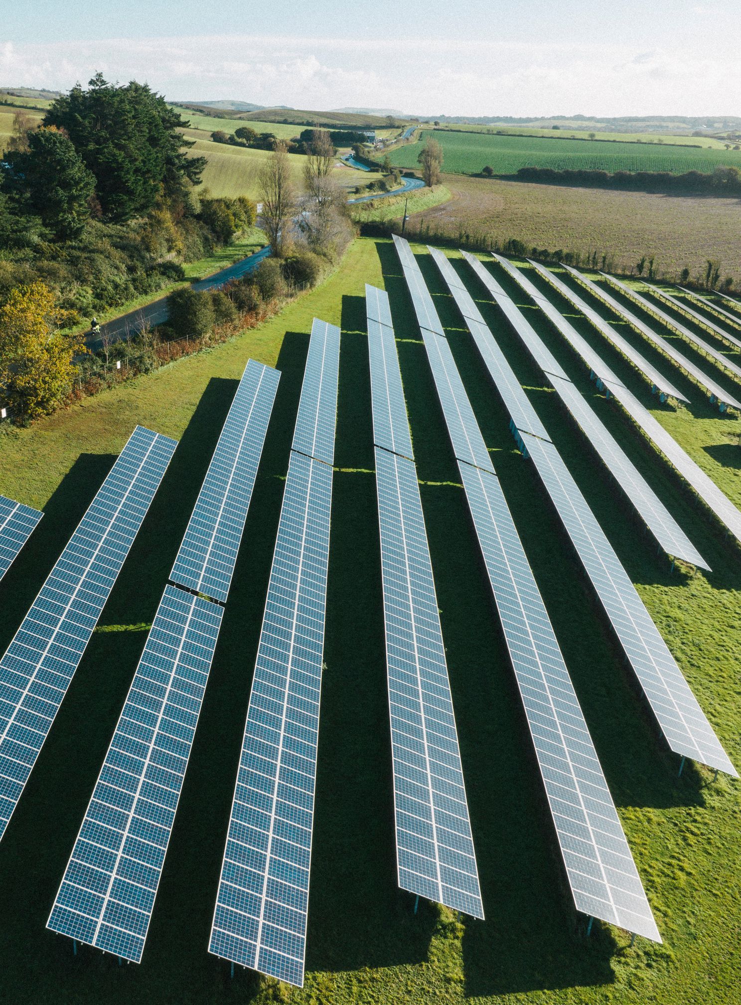 Rows of solar panels in a green field, generating clean energy. Countryside background.