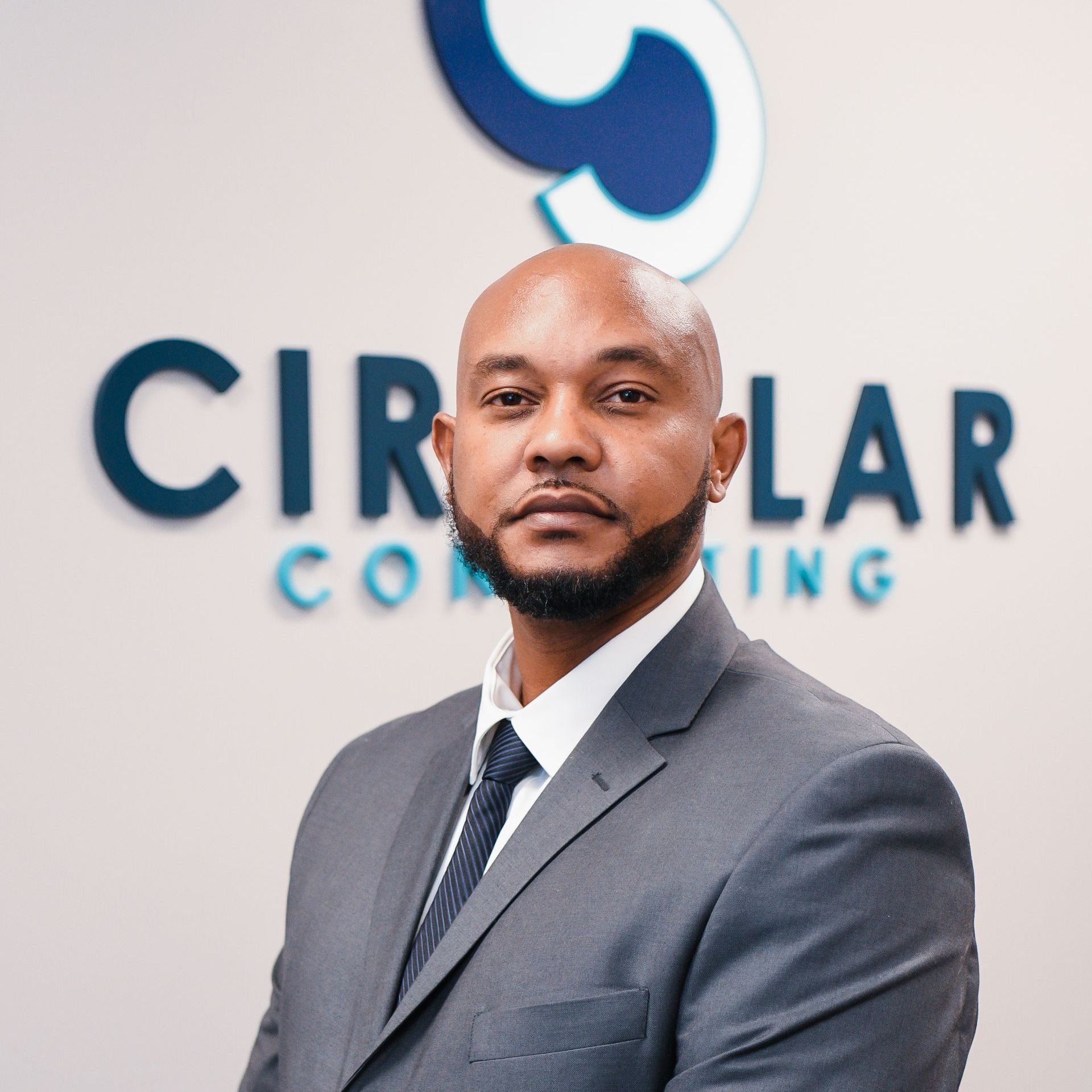 a man in a suit and tie is standing in front of a circular consulting sign