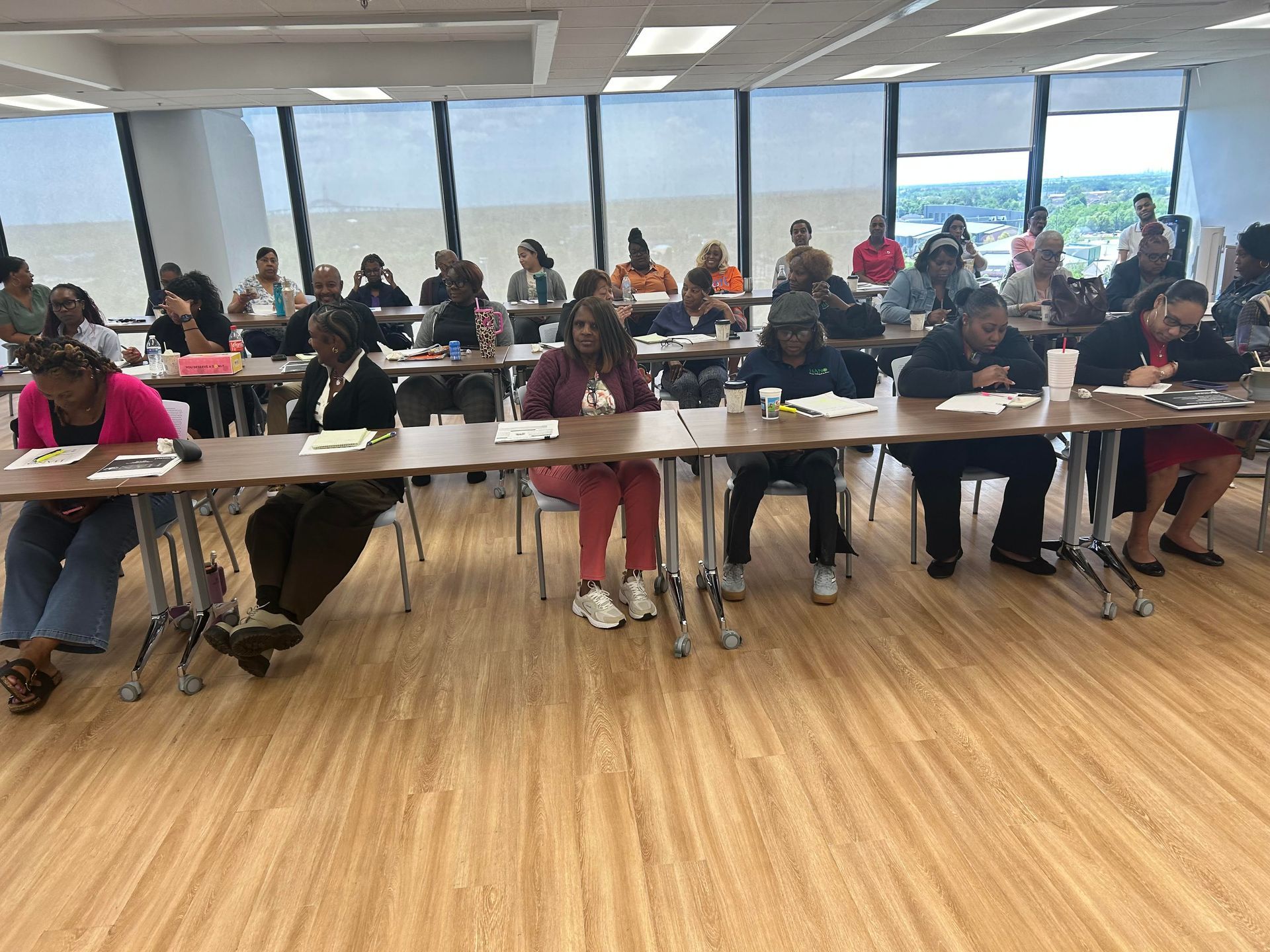 A group of people are sitting at tables in front of a projector screen.