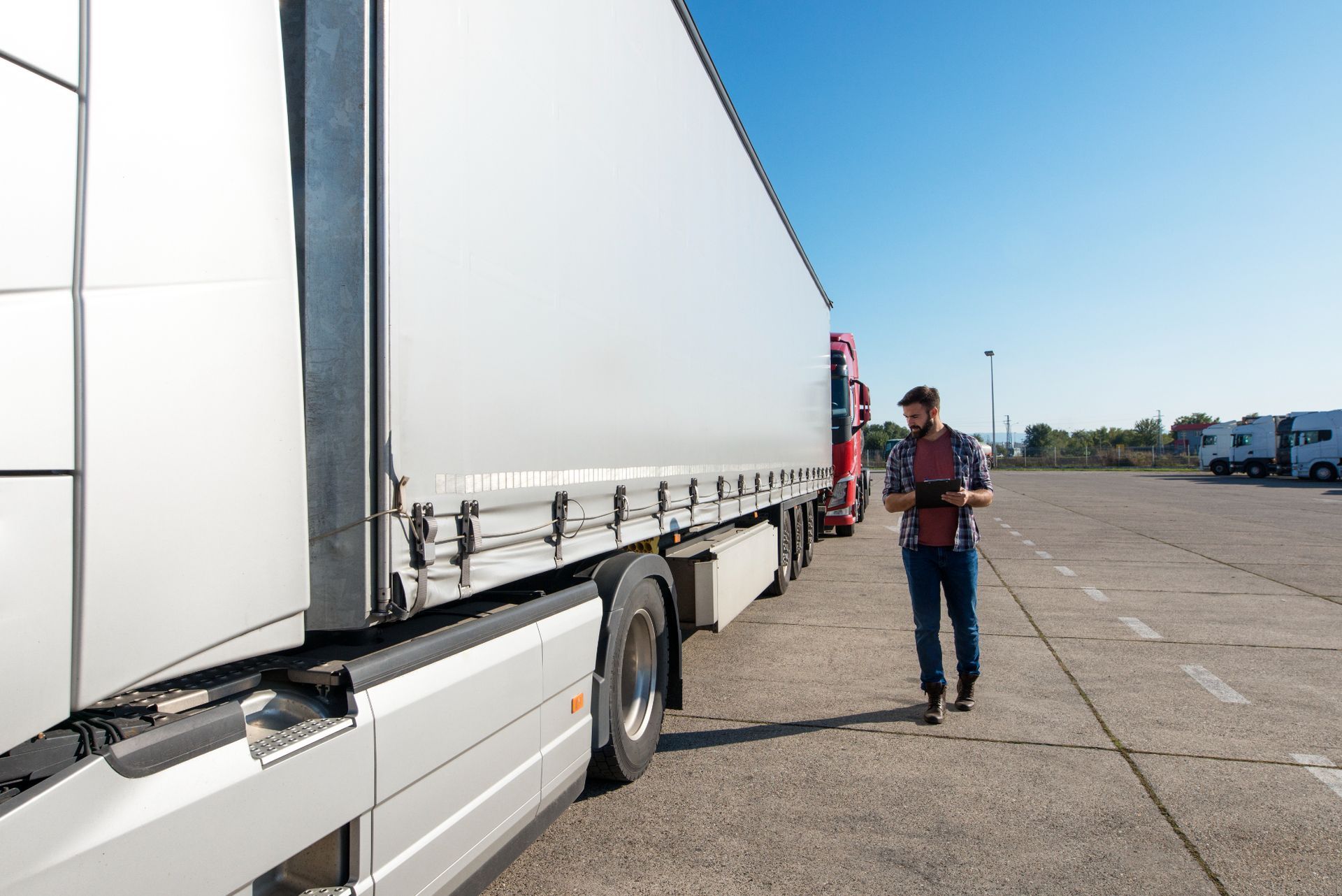 A man is standing next to a semi truck in a parking lot.