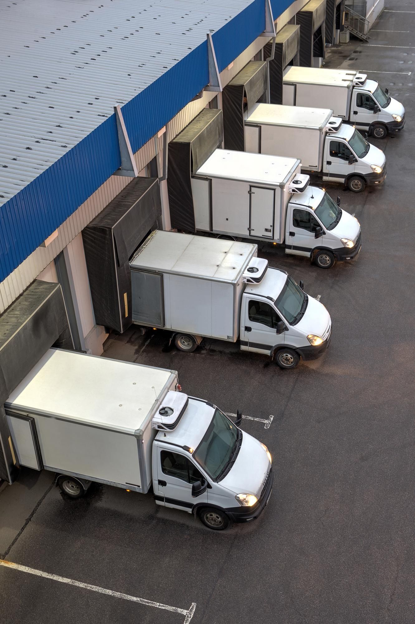 A row of white trucks are parked in front of a building
