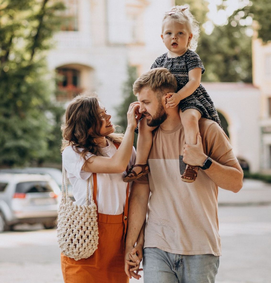 A man is carrying a little girl on his shoulders.
