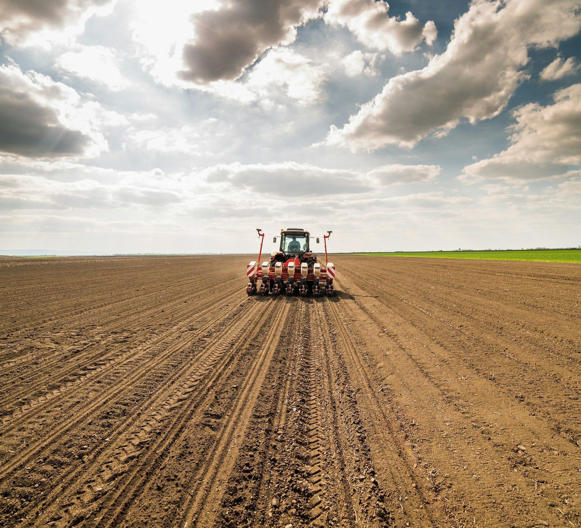 A tractor is plowing a field under a cloudy sky.