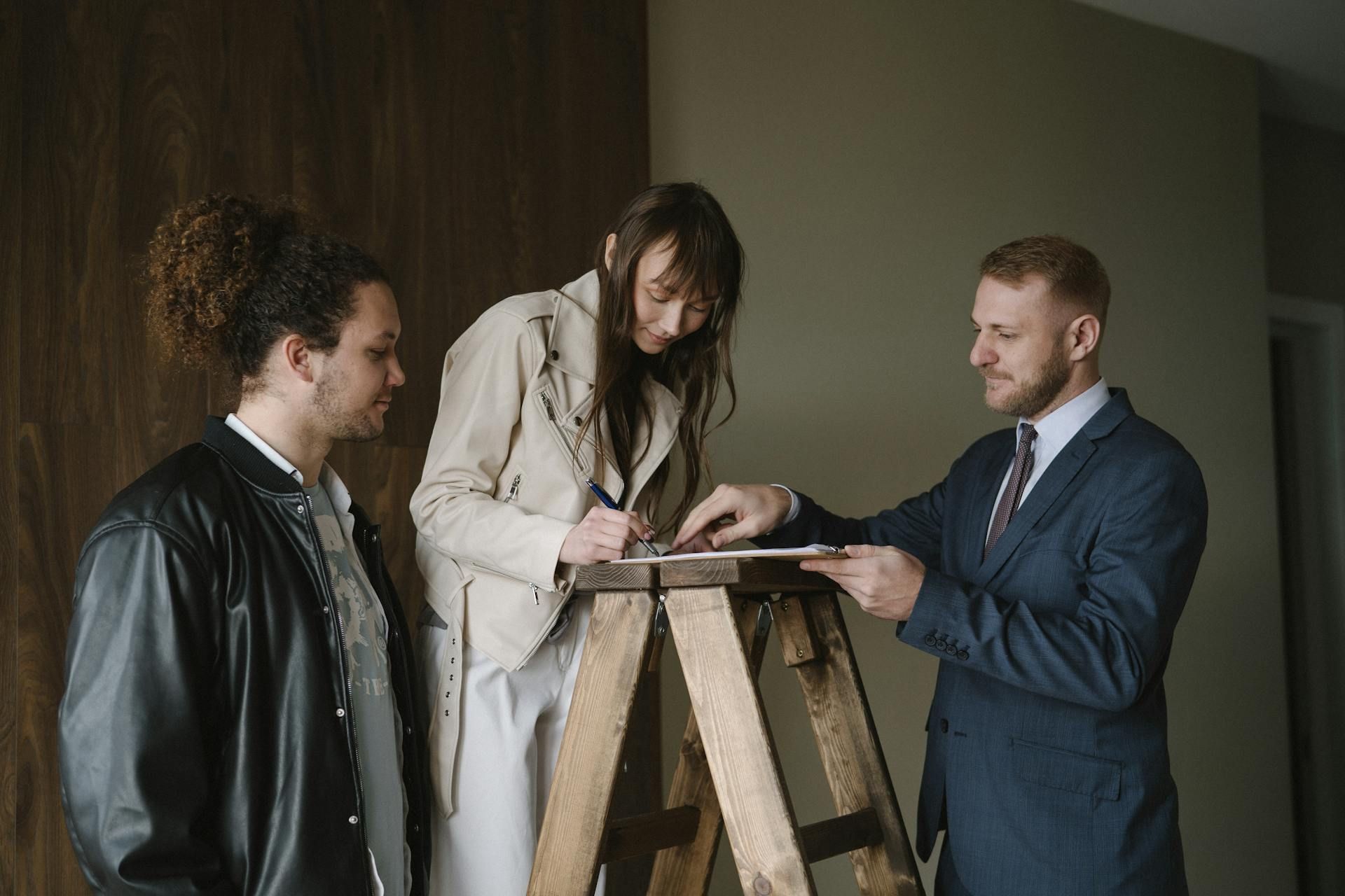 A group of people are standing around a wooden ladder.