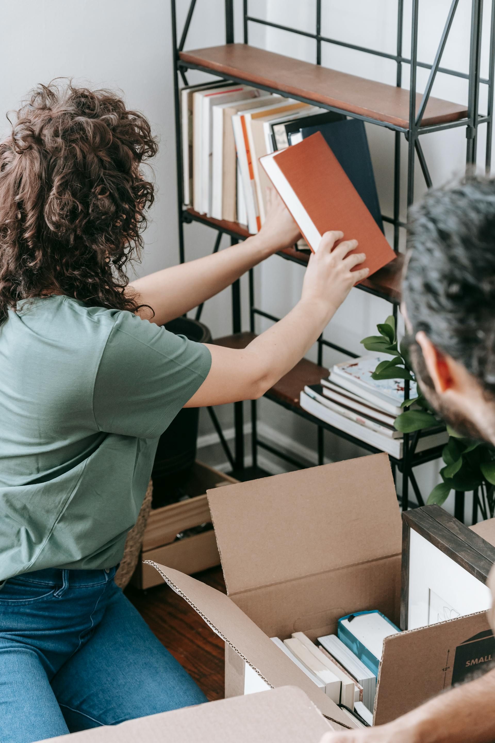 A woman is taking a book out of a cardboard box.