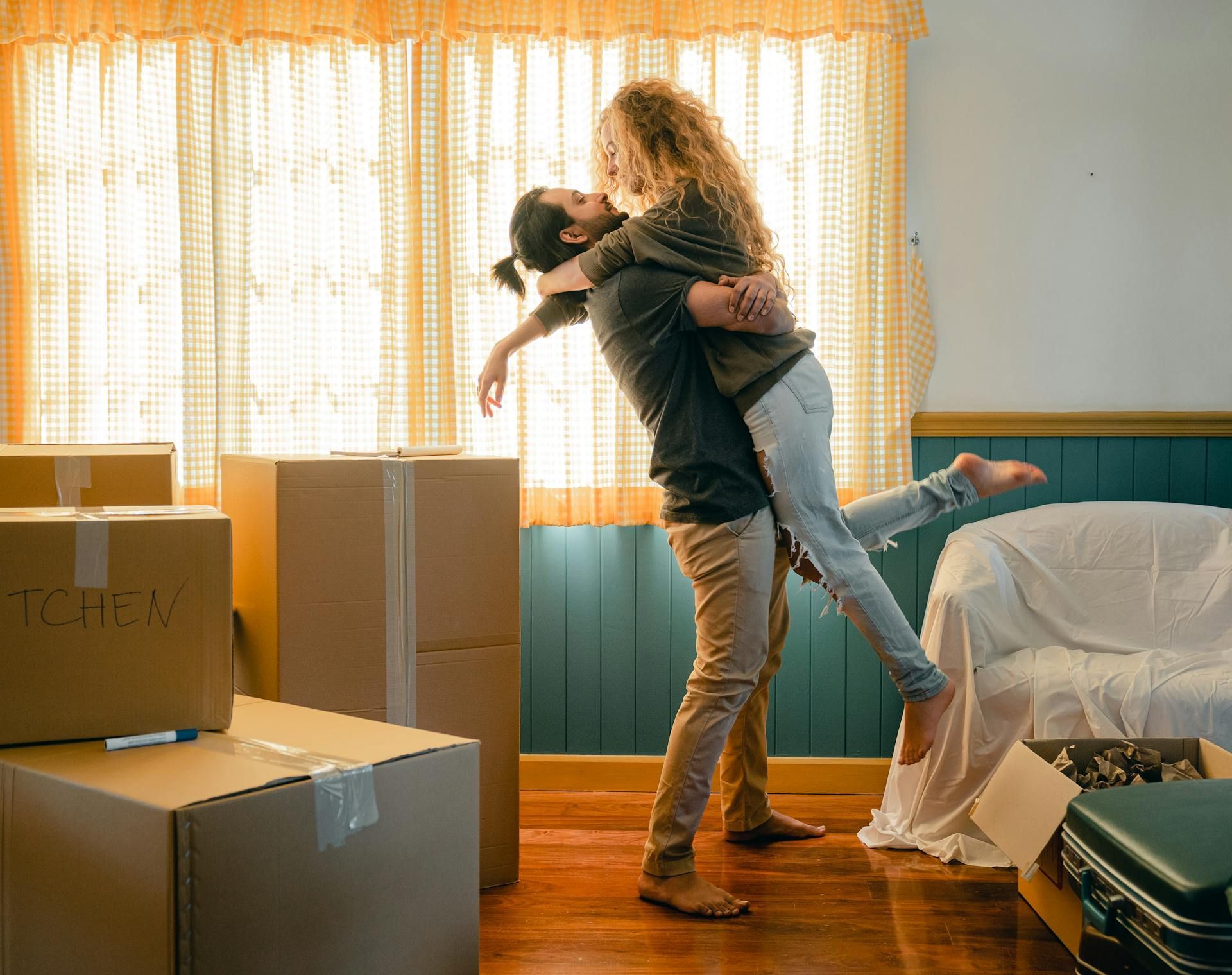 A man is holding a woman in his arms in a living room.