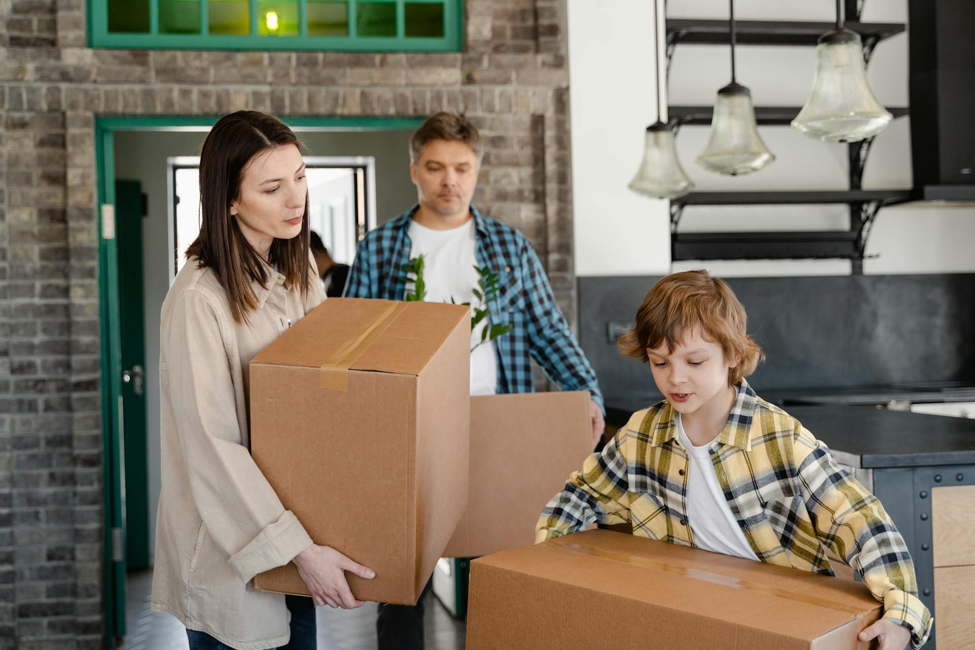 A family is moving into a new home and carrying boxes.