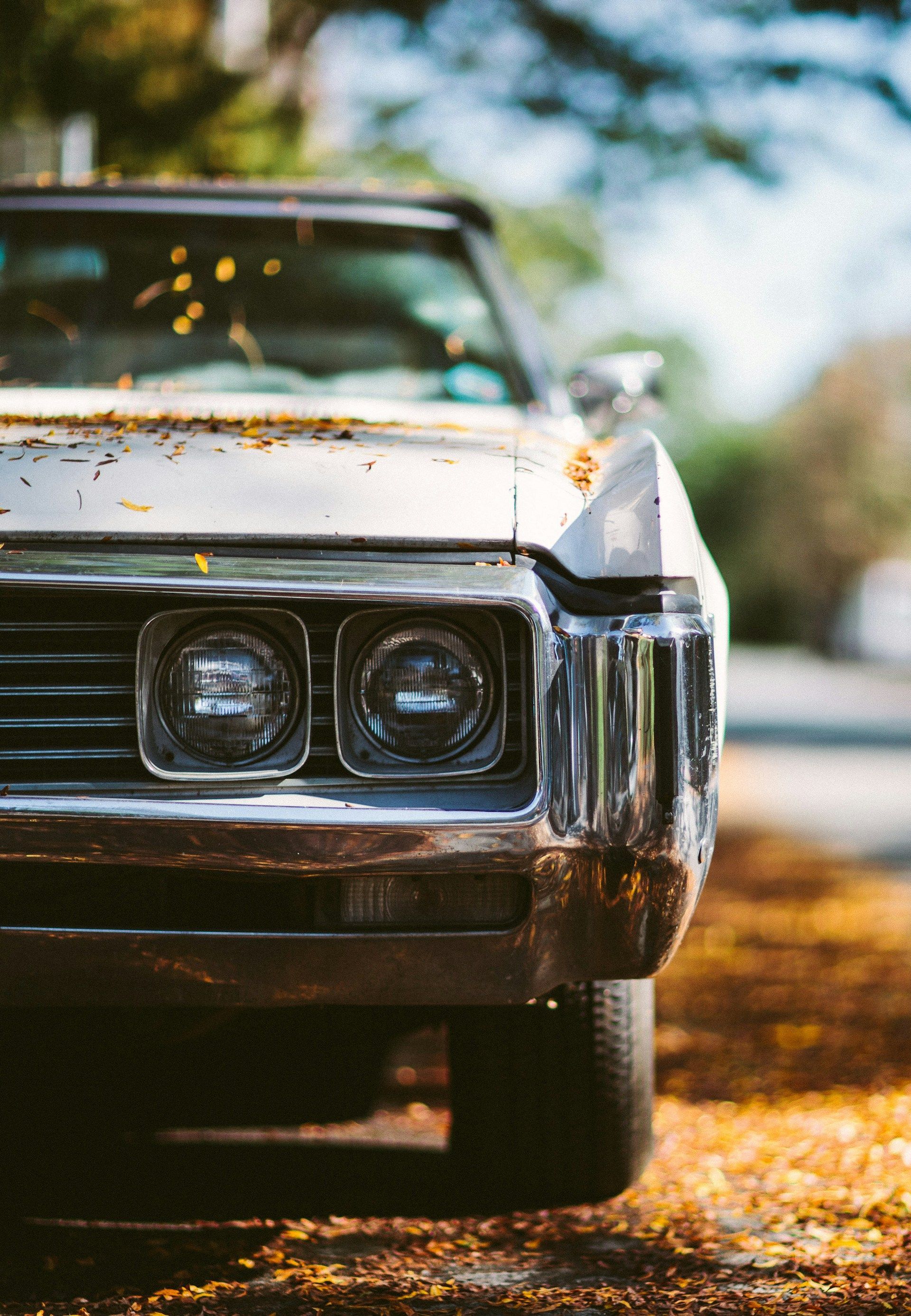 A close up of an old car parked on the side of the road.