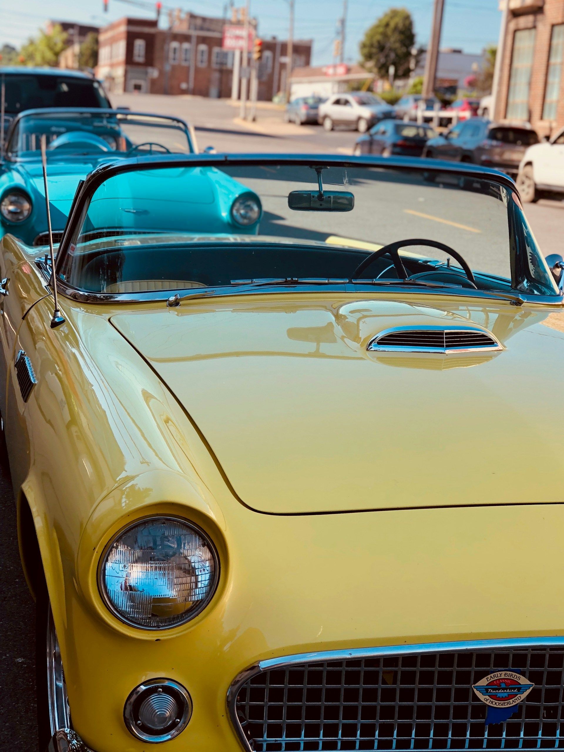 A yellow convertible is parked on the side of the road.