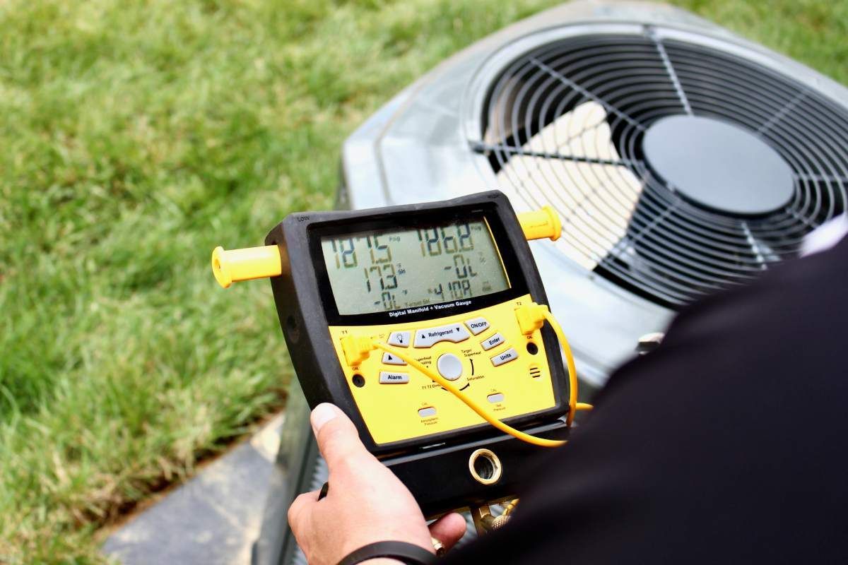 An HVAC technician servicing an outdoor HVAC unit