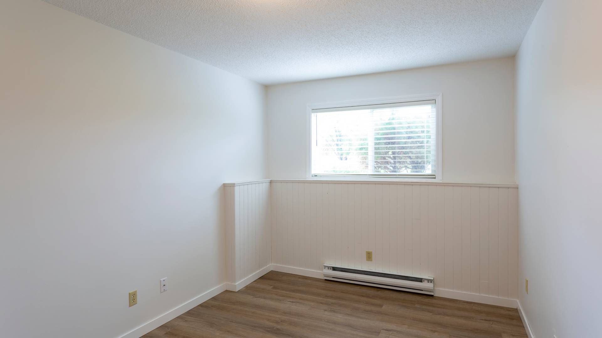 A baseboard heater in a white, empty room with a small, horizontal window at Advantage Air HVAC near