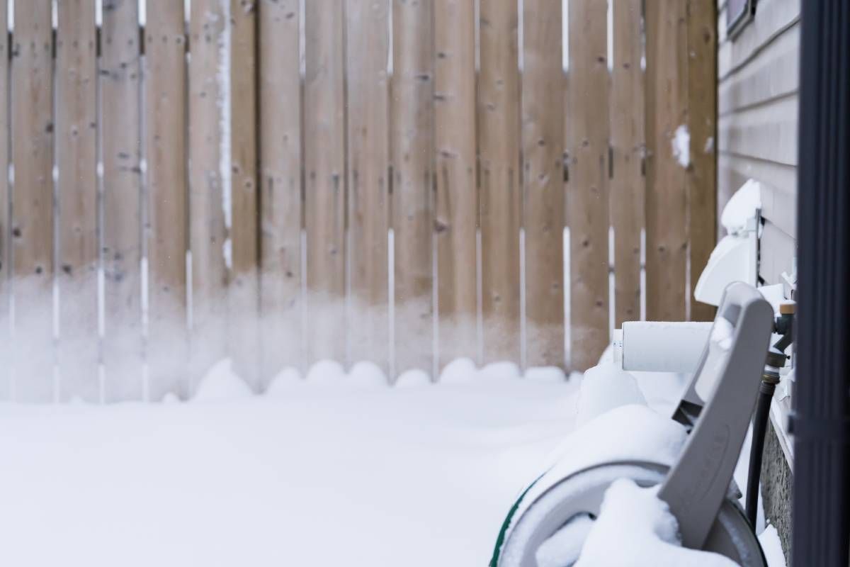 A furnace exhaust pipe letting out steam into the dry air in a snowy backyard at Advantage Air HVAC near Lexington, KY