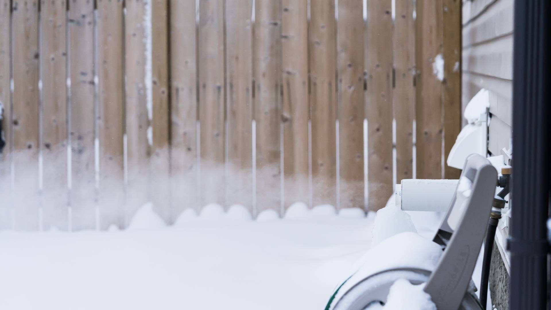 A furnace exhaust pipe letting out steam into the dry air in a snowy backyard at Advantage Air HVAC 