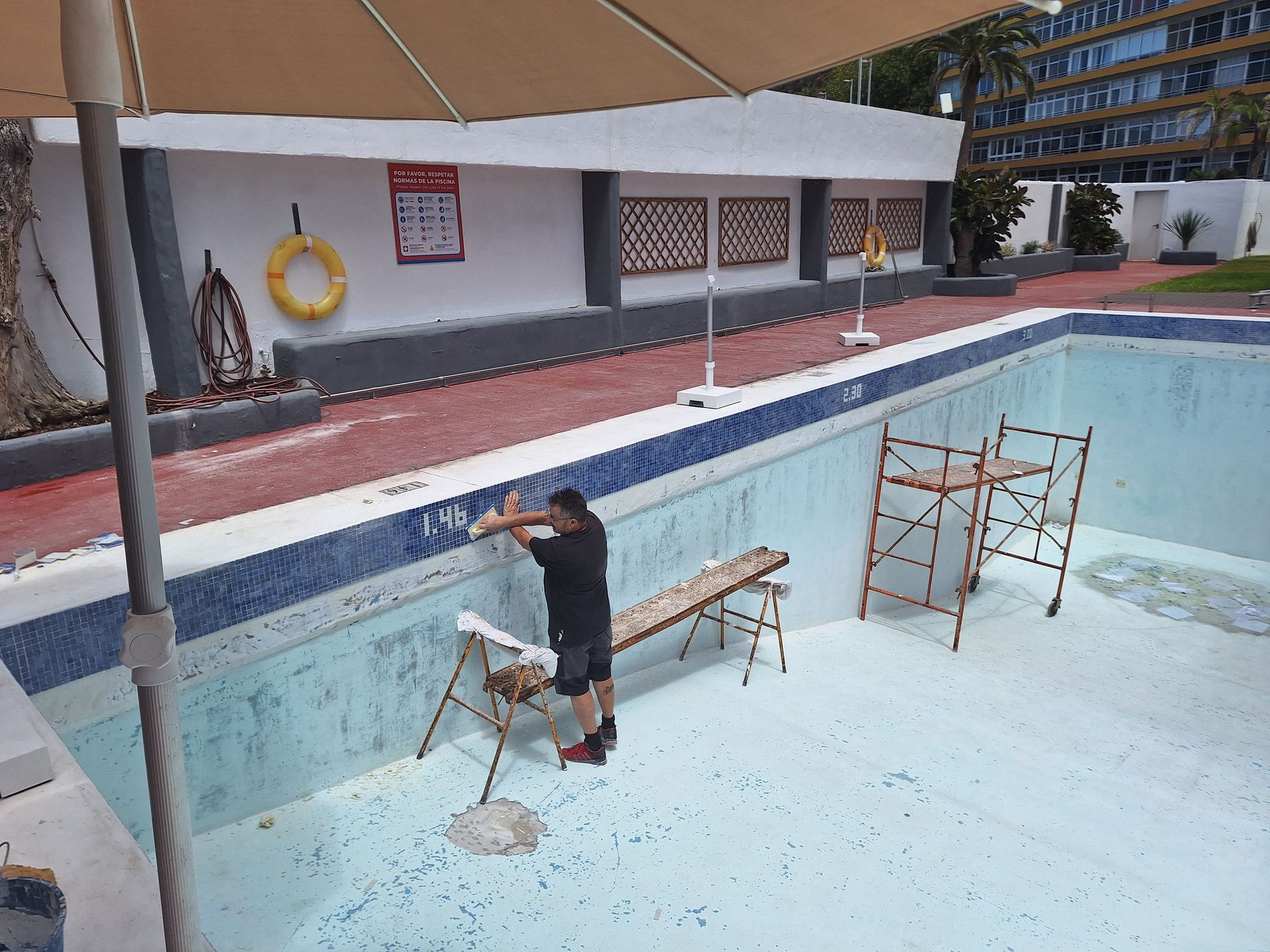 Un hombre está limpiando una piscina con un trapeador.