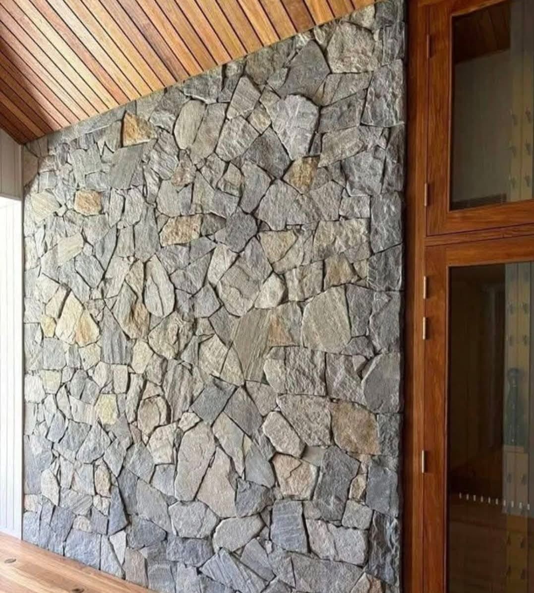 Una pared de piedra con un techo de madera y una puerta de cristal.