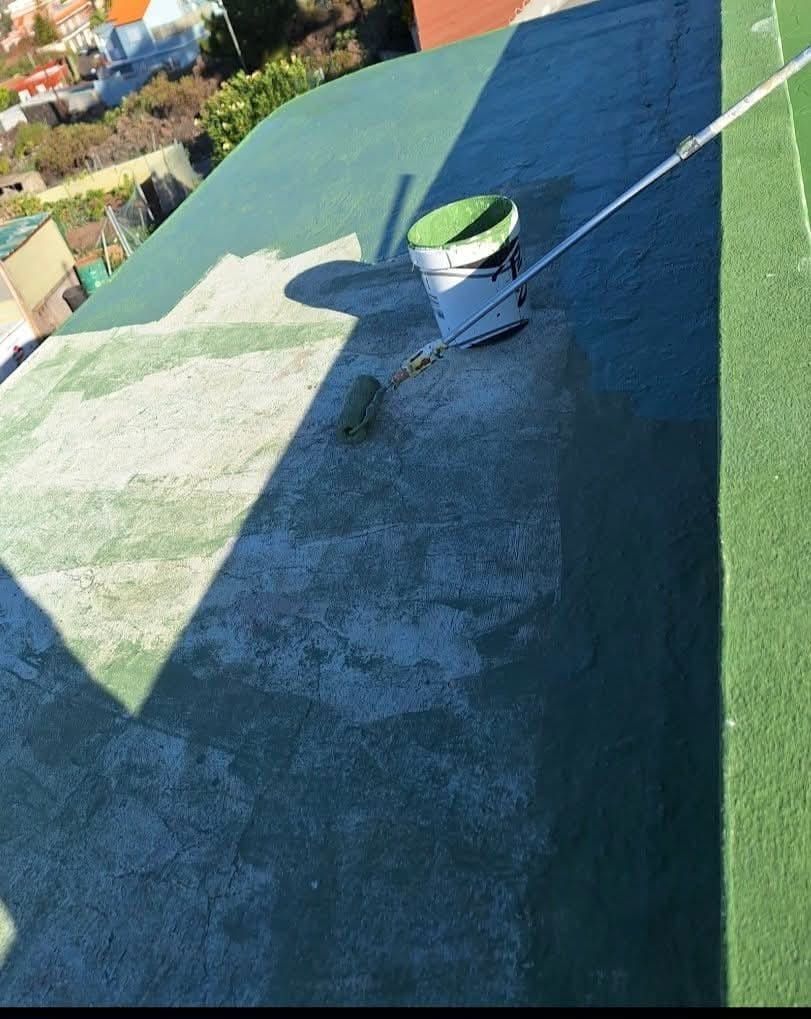 Un balde de pintura está encima de un techo verde.