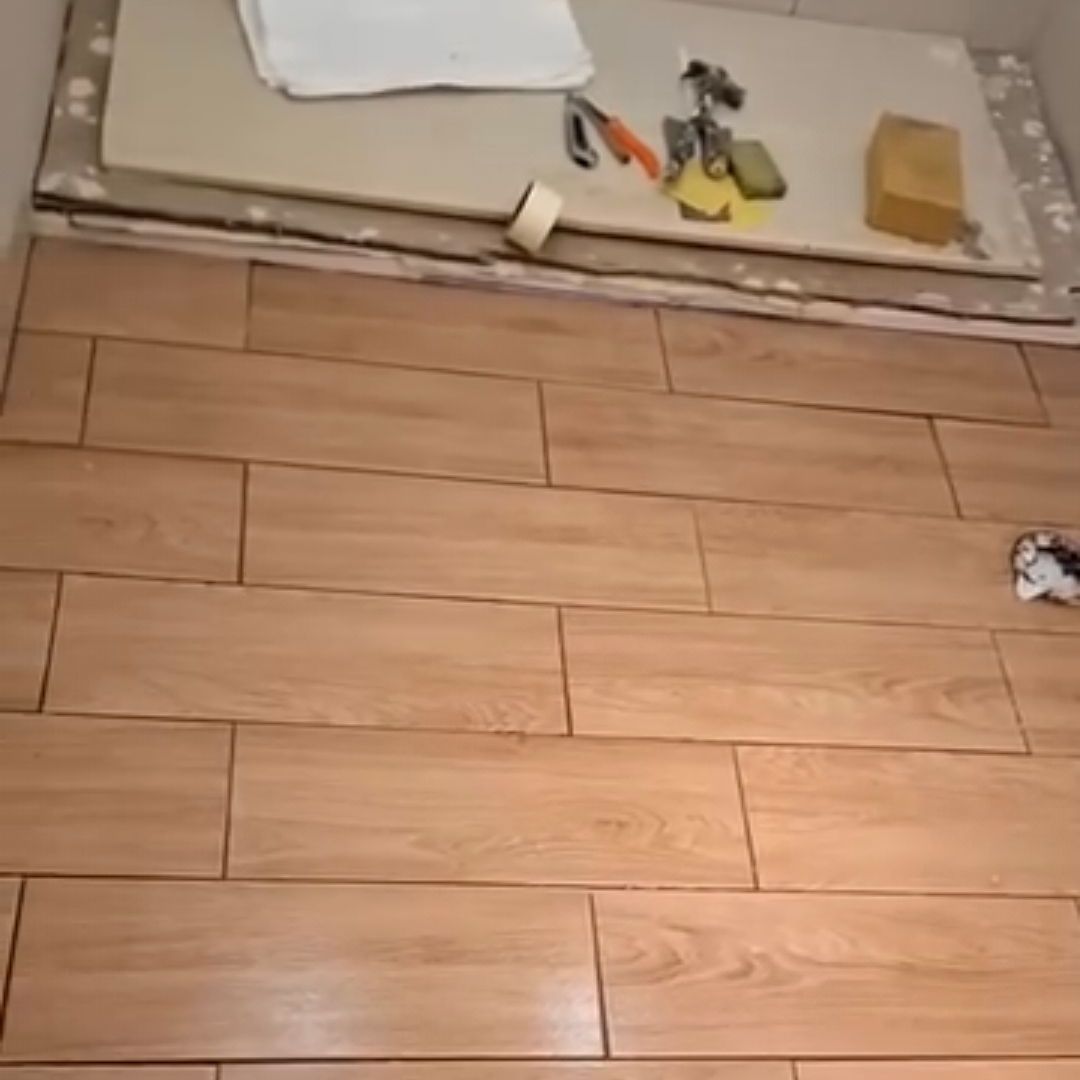 Un piso de madera con baldosas y herramientas sobre él.