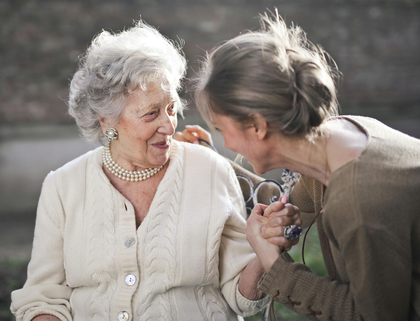 Baby wearing a striped hat and onesie, smiling and waving, lying on a white fluffy rug.