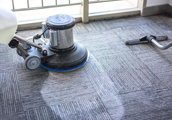 Floor buffer cleaning carpet in a bright room by the windows