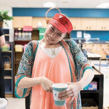 Elli Hofmeister in a store with a cup, smiling for the camera