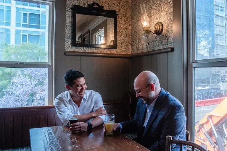 Craig Ramirez and Andrew Hauser drinking beers in a pub.