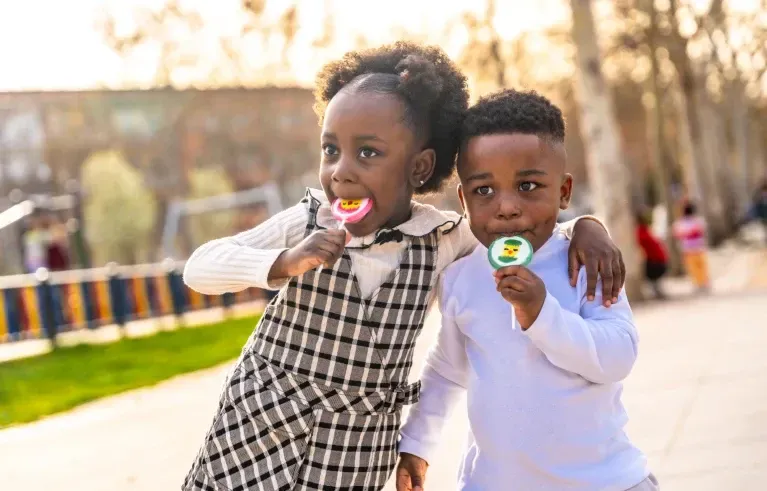 Two children licking lollipopos