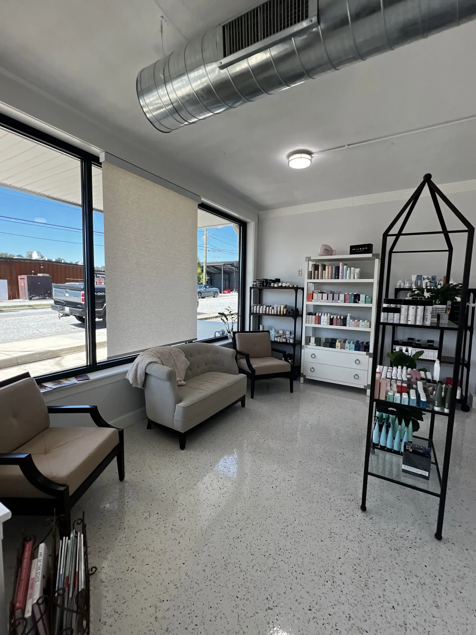 A living room with a couch , chairs , shelves and a window.