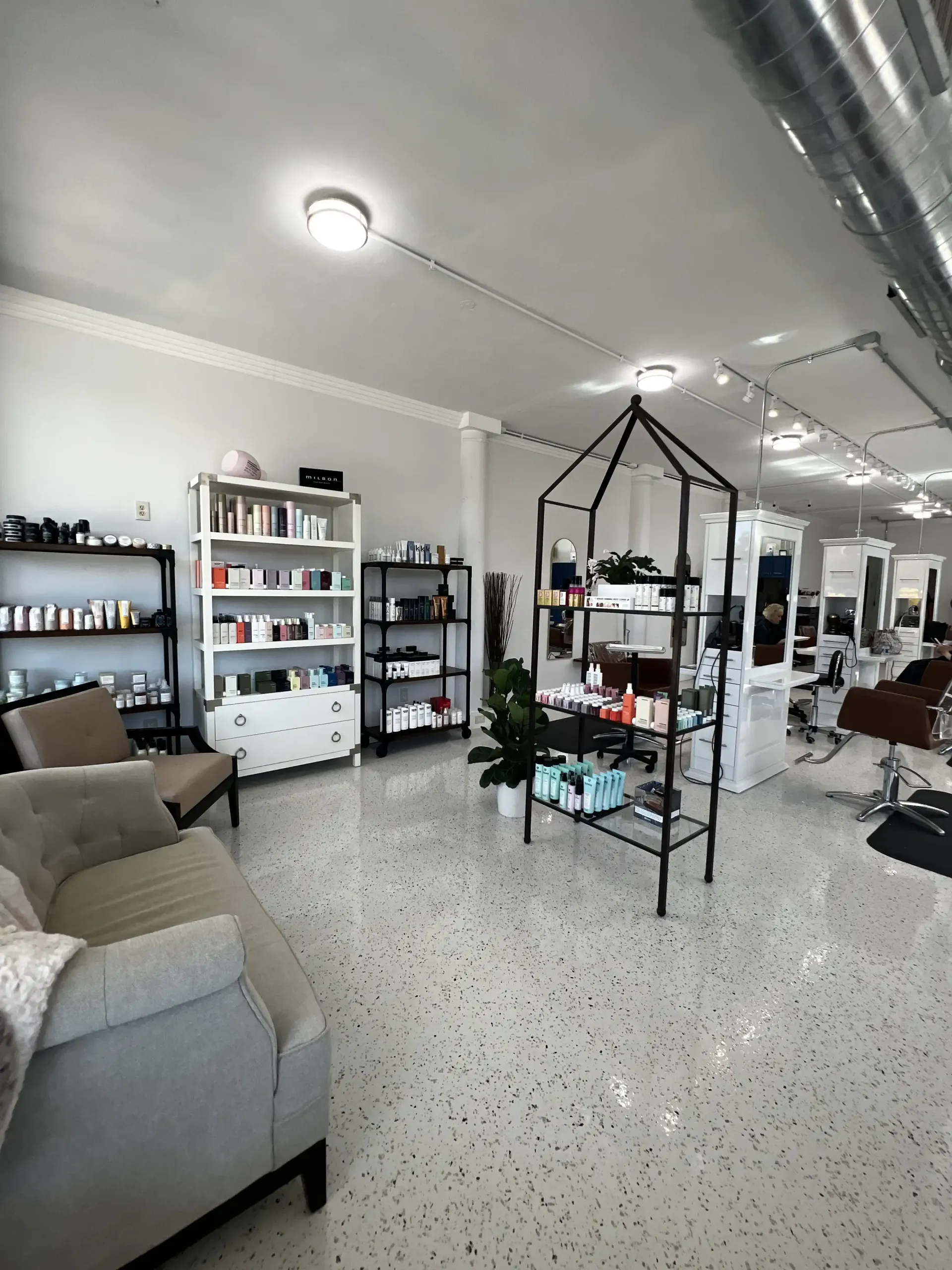 A salon with a couch , chairs , shelves and chairs