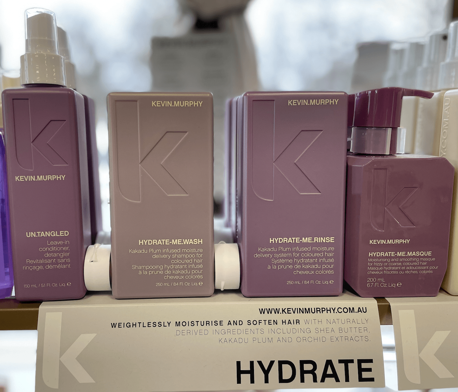 Several bottles of hydrate hair products are lined up on a shelf