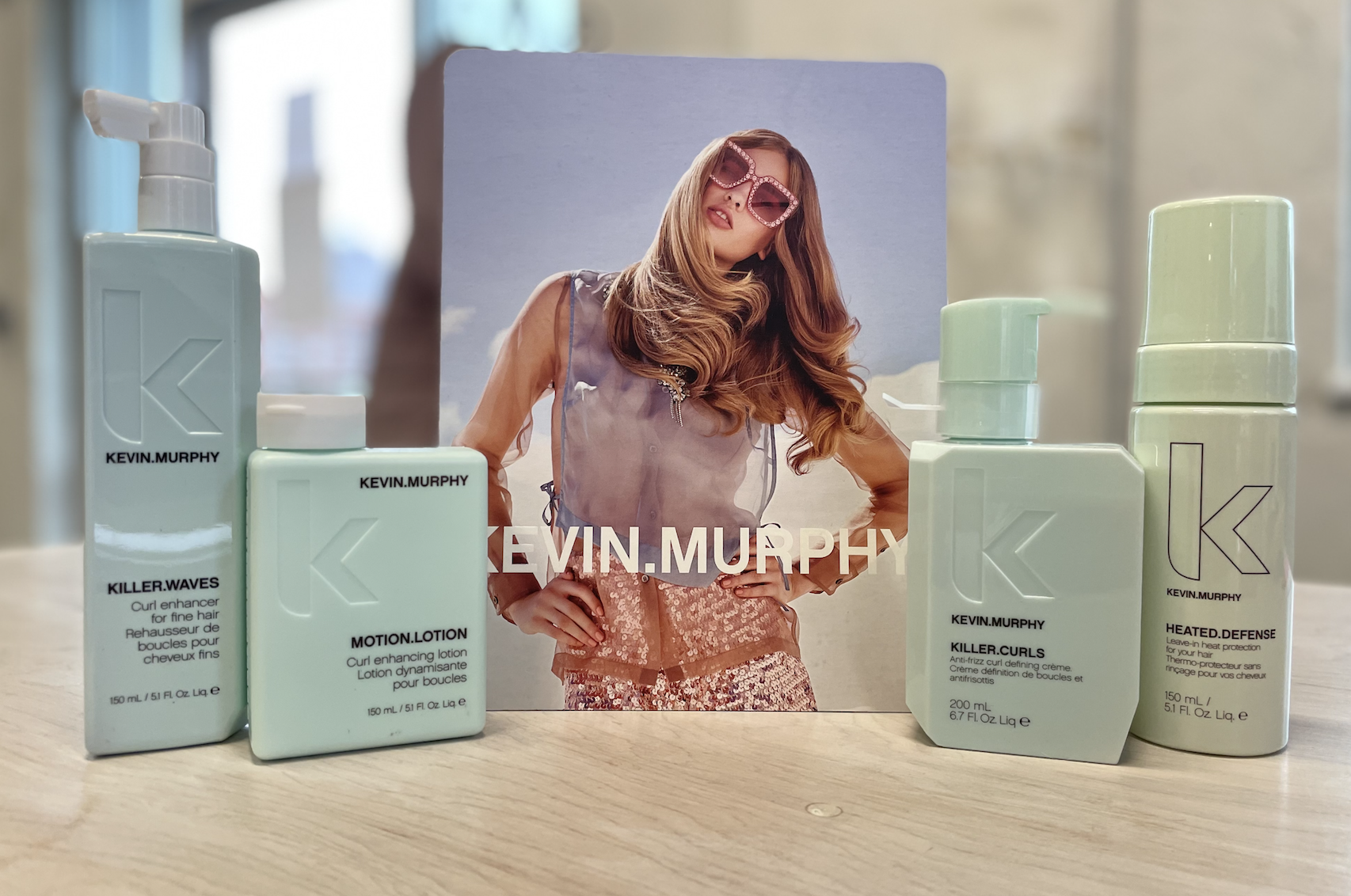A woman is standing in front of bottles of kevin murphy hair products