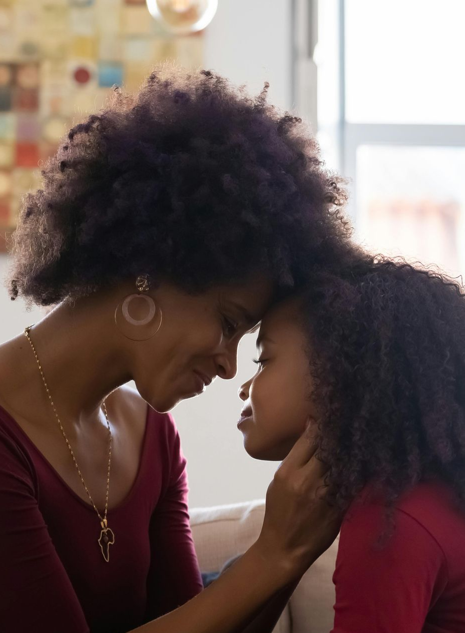 Mother and daughter, touching forehead, symbolizing connection, care, and women’s health support.