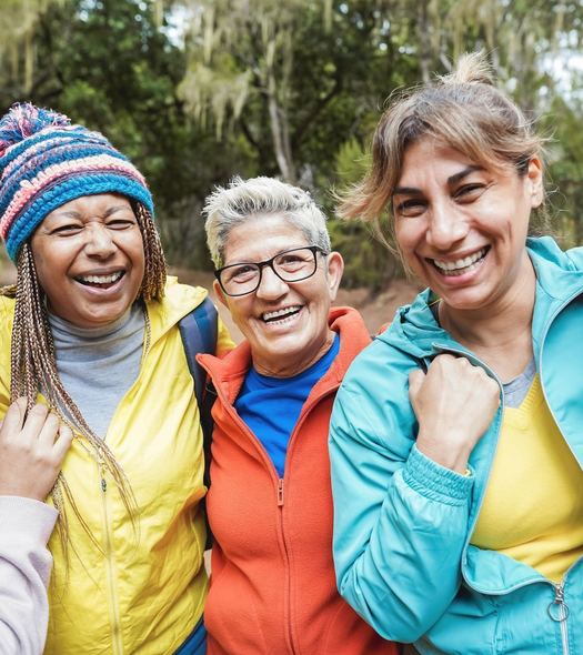 A diverse group of women, smiling together, representing community and shared women’s health experiences.