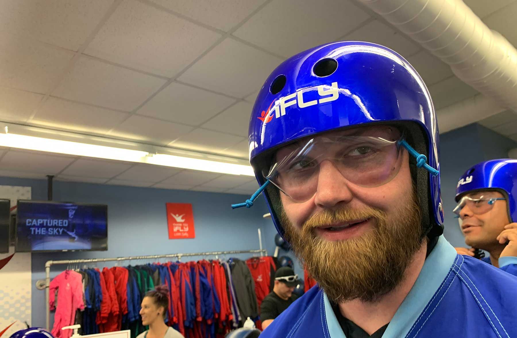 A man with a beard is wearing a blue helmet and glasses.