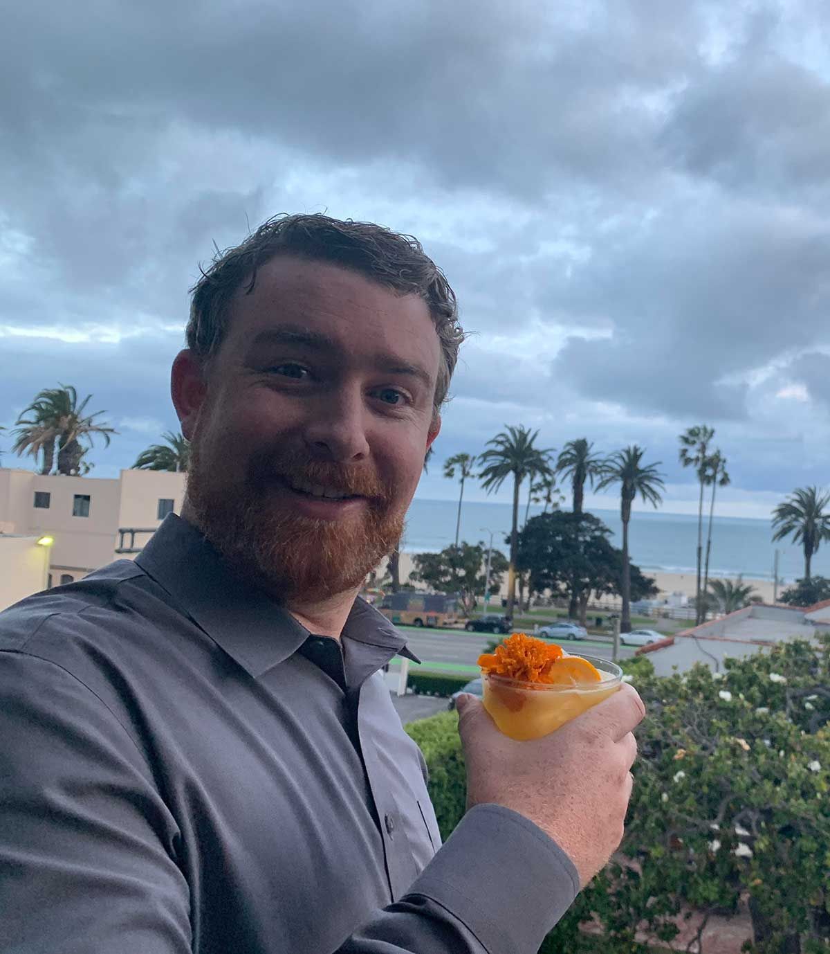 A man with a beard is holding a drink in his hand.