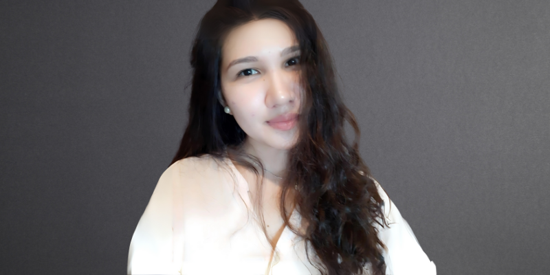 A woman with long hair is wearing a white shirt and looking at the camera.