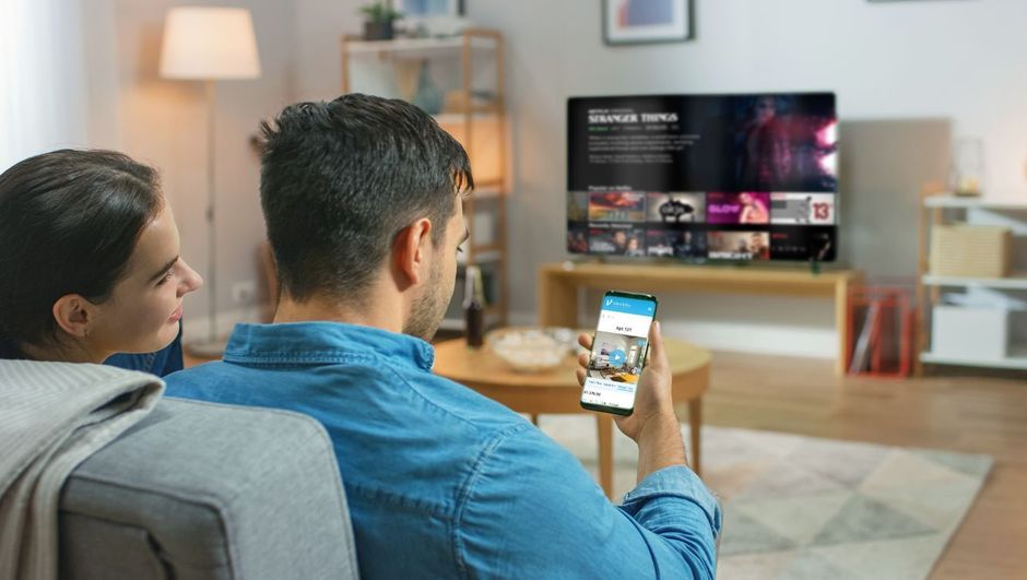 A man and a woman are sitting on a couch watching tv.
