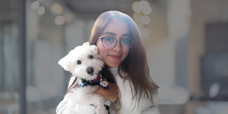 A woman is holding a small white dog in her arms.
