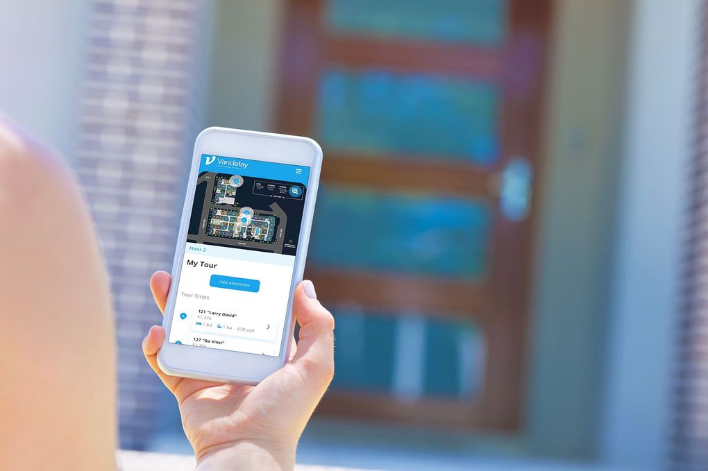 A person is holding a cell phone in their hand in front of a door.