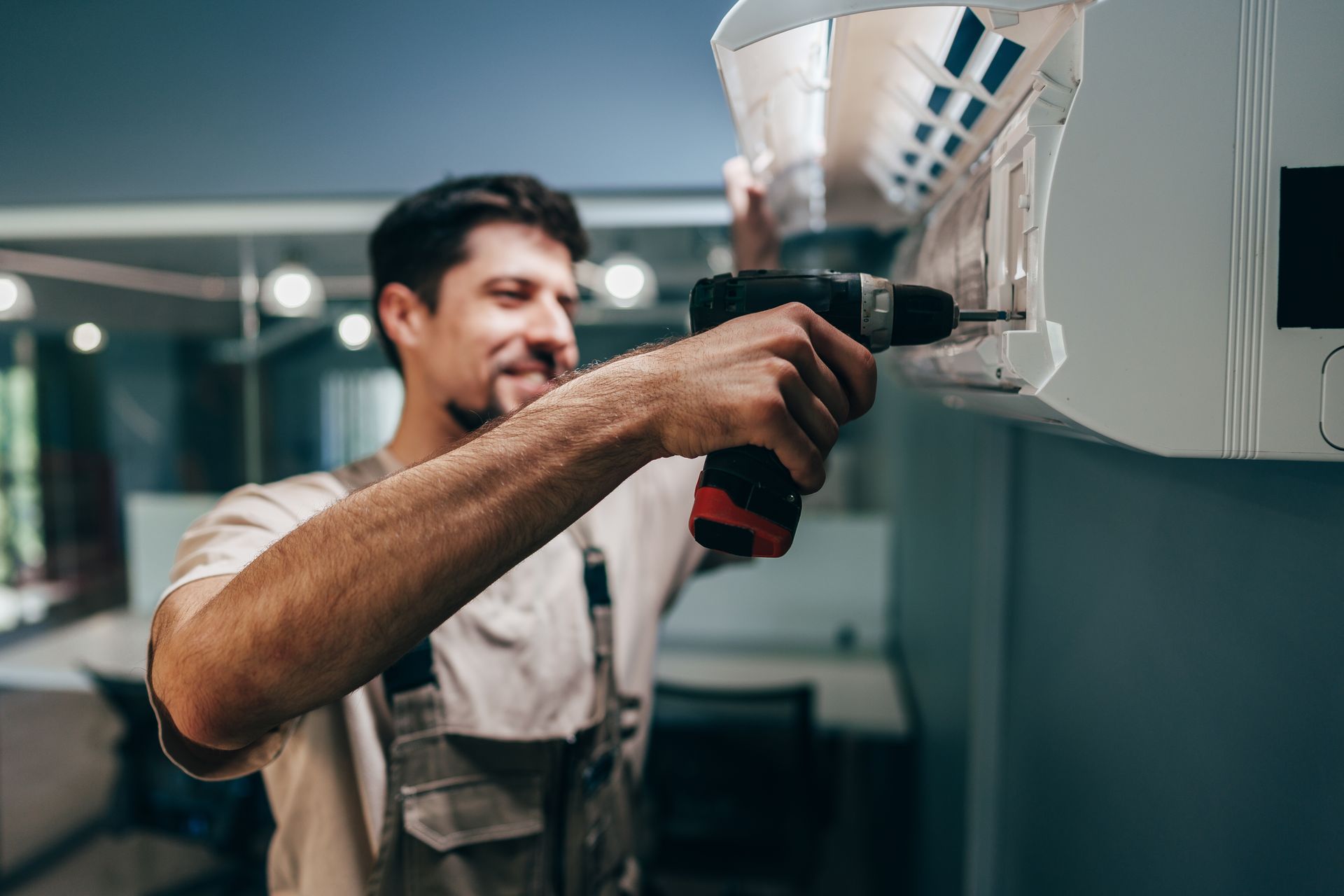 Man using a power drill to install an air conditioning unit.