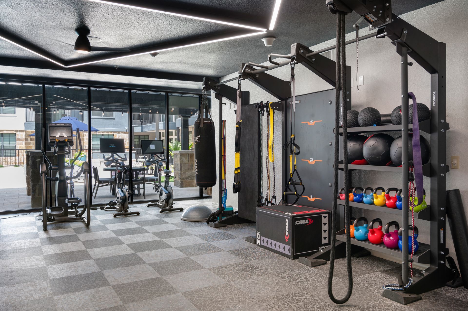 Gym with weights, exercise machines, and a punching bag in front of a glass wall.