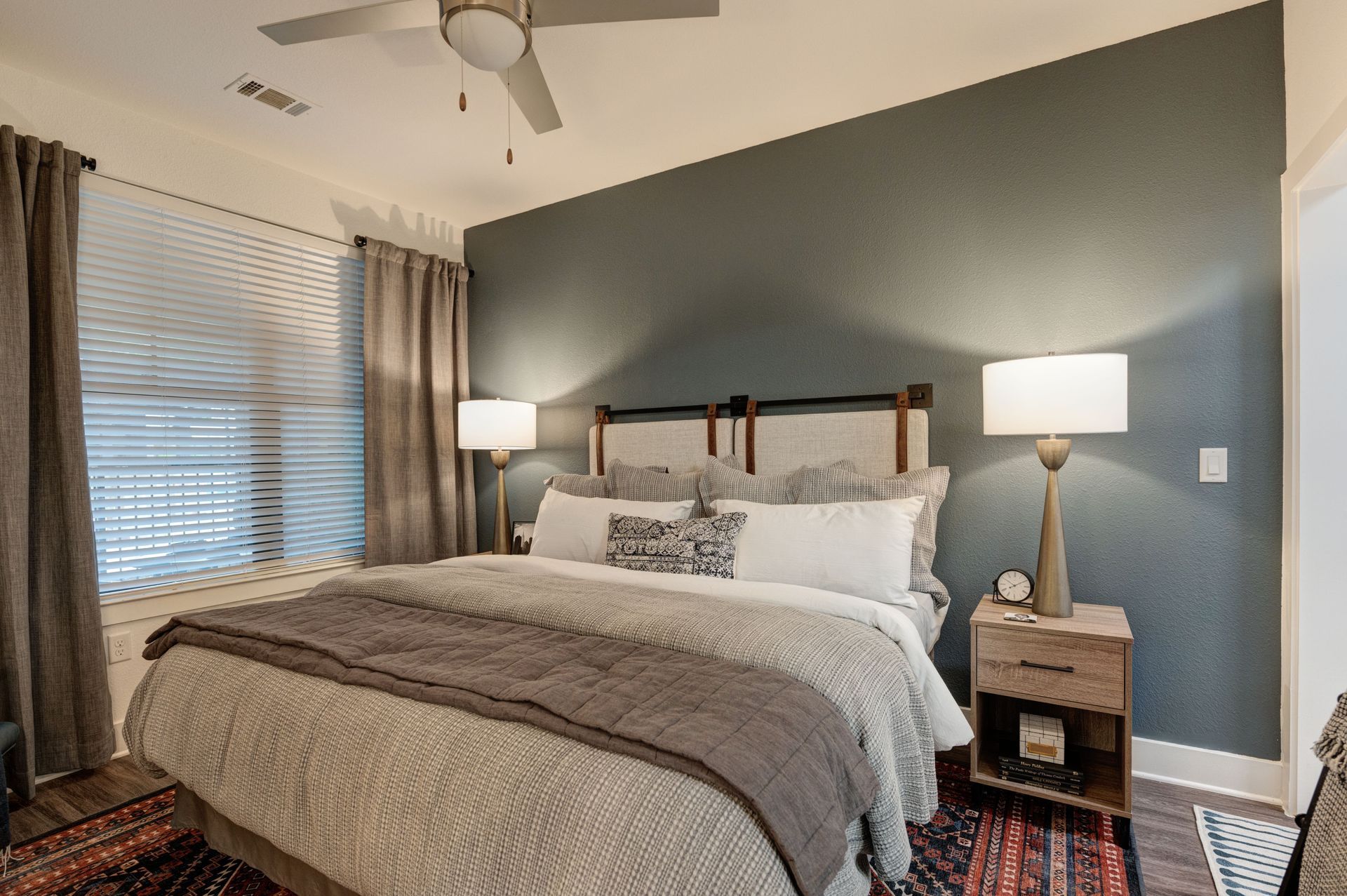 Bedroom with a bed, nightstands, and accent wall. Neutral tones with a teal wall.