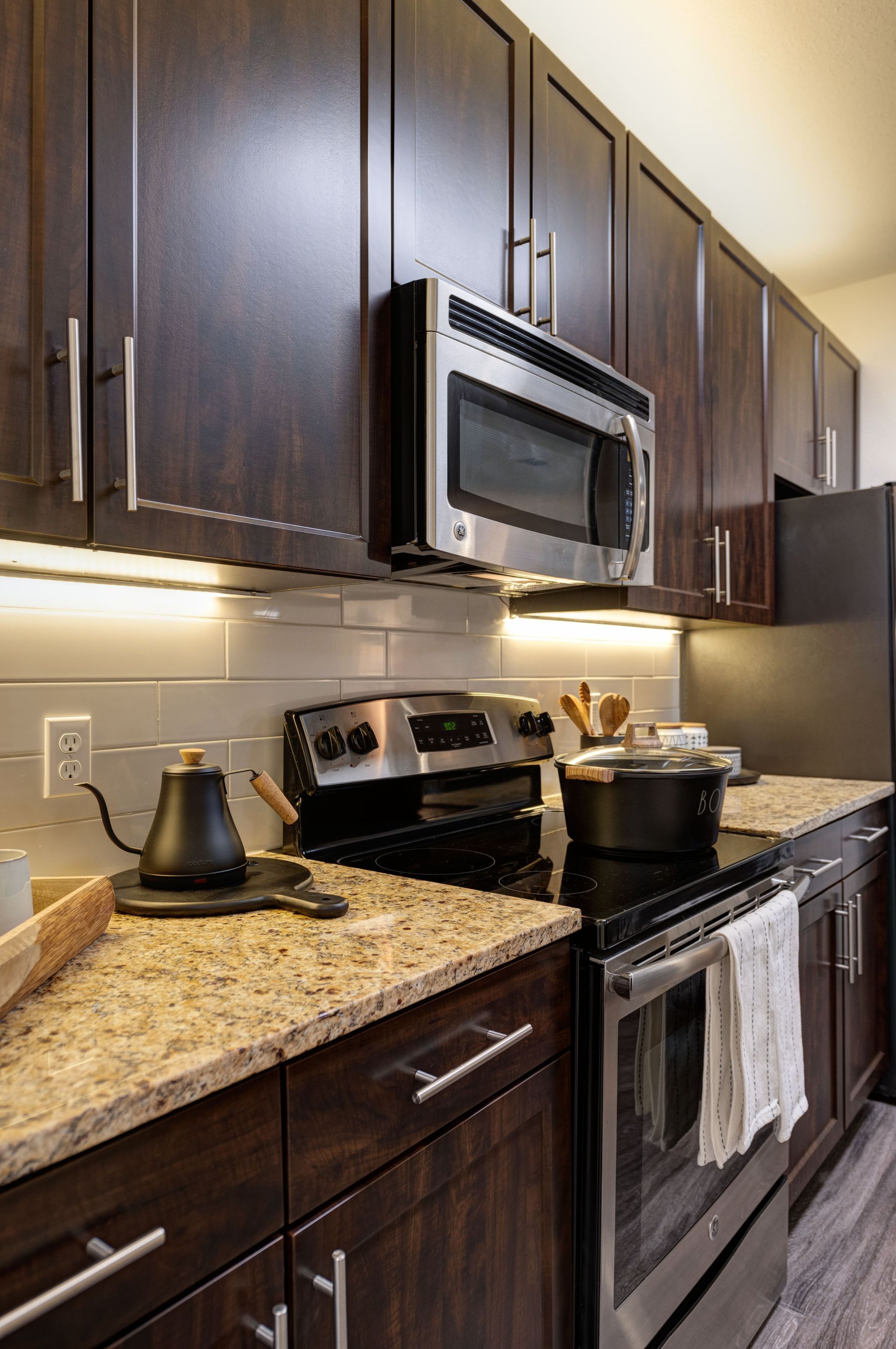 Dark wood kitchen cabinets, granite countertops, stainless steel appliances, and white backsplash.
