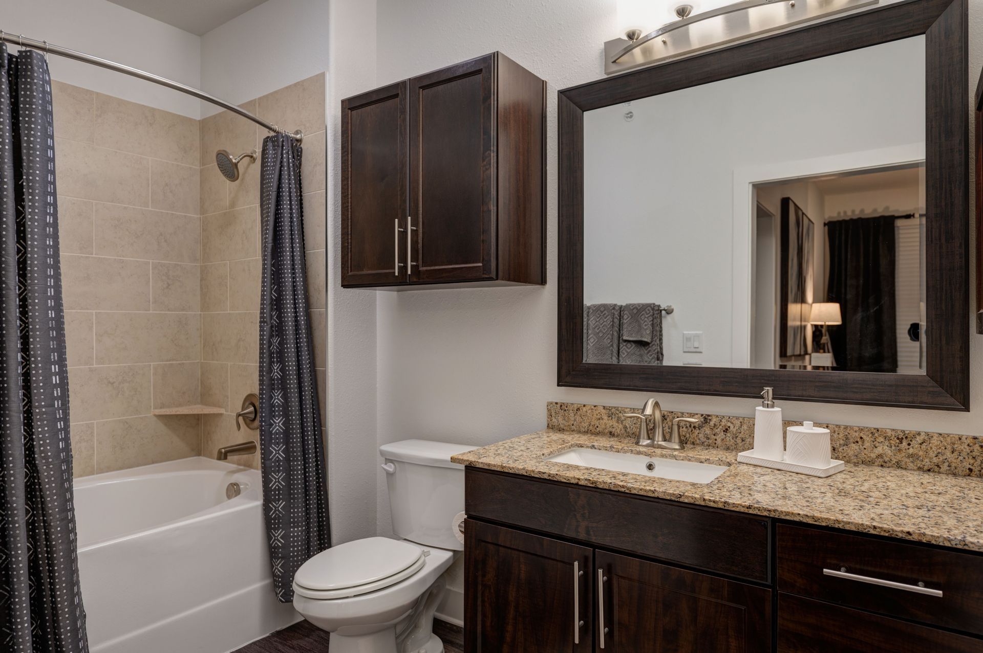 Bathroom with dark brown cabinets, beige walls, and a granite countertop.