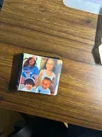 Stack of photos on a wooden desk showing four children smiling.