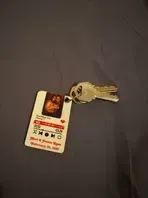 Keys attached to a keychain with a couple's photo and text on a gray surface.