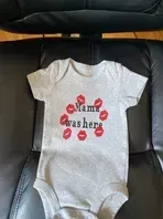 Gray baby onesie with red kiss marks and text 